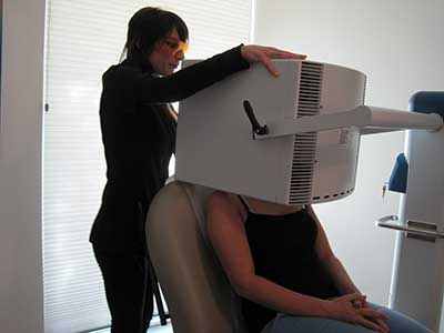 Esthetician Anne Marie Johnson performs a blue light therapy treatment on a patient.